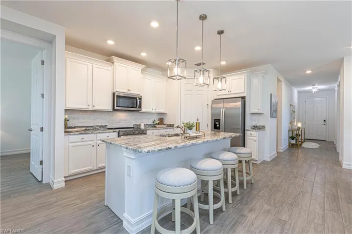 Kitchen with large granite island & white cabinetry