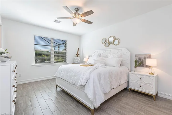 Primary Bedroom with wood like tile floors and ceiling fan, large window out to pool area