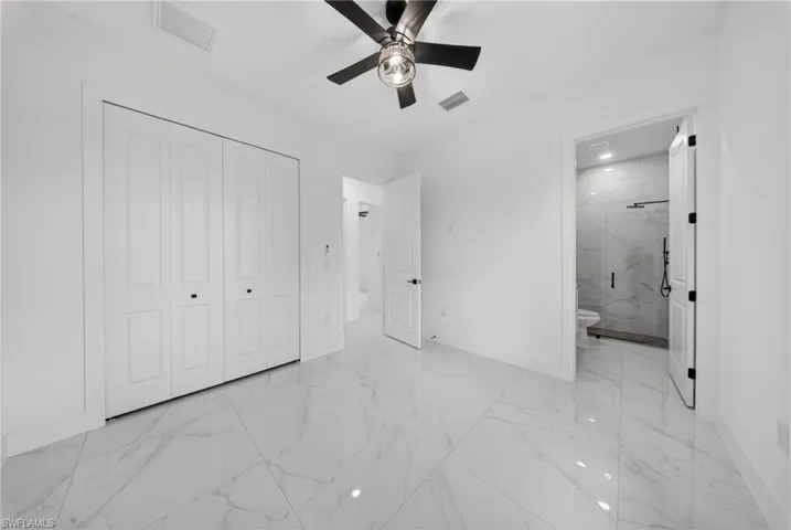 Spacious room featuring large format white tile flooring, a modern ceiling fan with integrated lighting, and white bi-fold closet doors