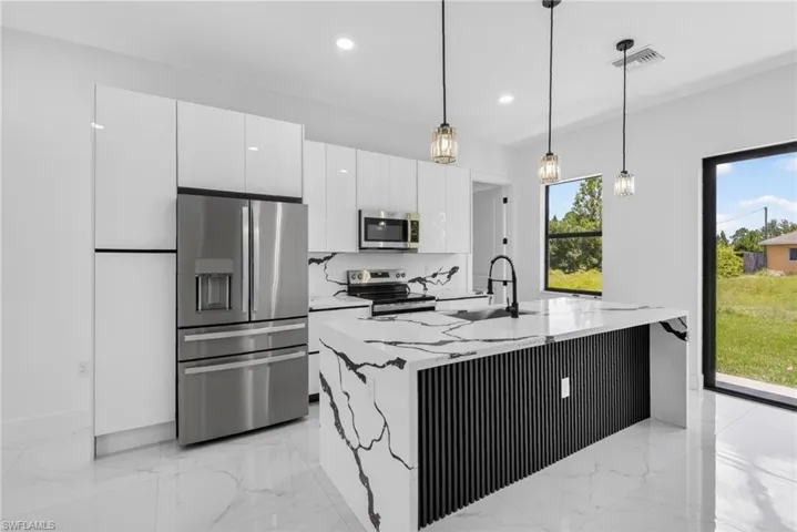 Contemporary kitchen featuring a waterfall island with a slatted black panel base, complemented by matching countertops and backsplash