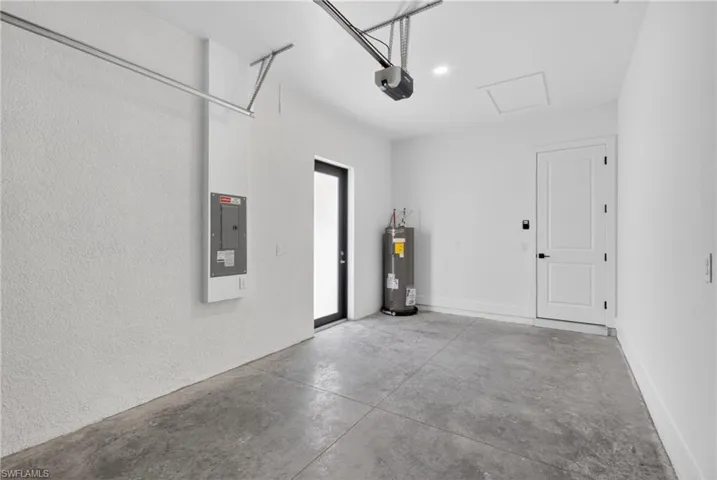 Garage space featuring textured white walls, a concrete floor, and an overhead garage door opener