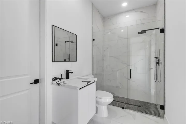 Bathroom featuring a glass-enclosed shower with black fixtures and a patterned floor