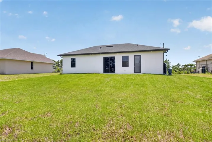 Expansive rear yard featuring a newly constructed white stucco exterior