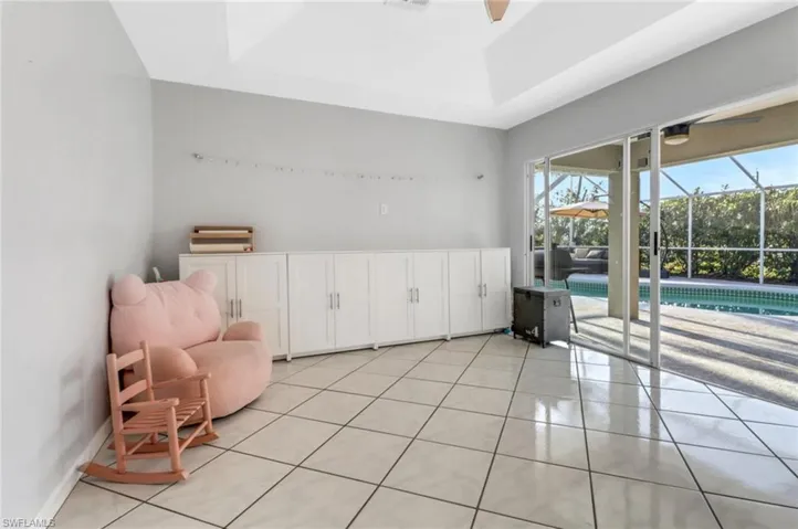 Living area featuring a wealth of natural light, a tray ceiling, light tile patterned flooring, and a sunroom