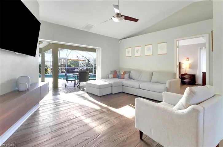 Living room with vaulted ceiling, a sunroom, ceiling fan, and hardwood / wood-style flooring