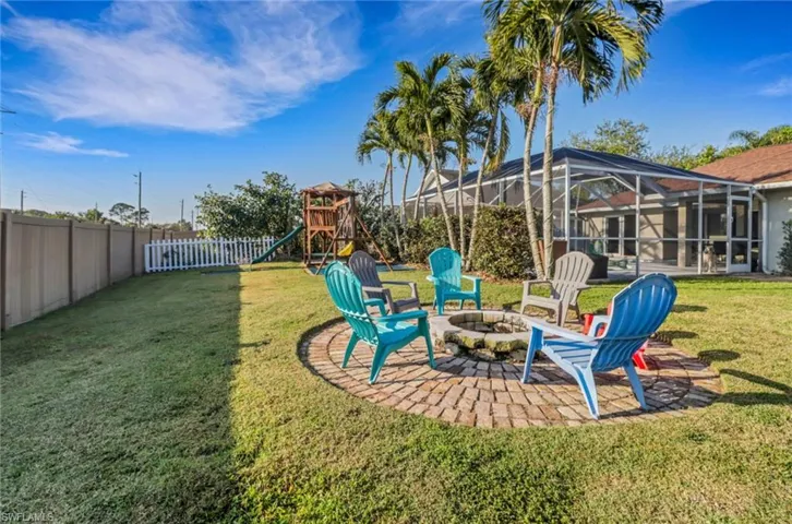 View of yard with a fire pit, a playground, a lanai, a fenced backyard, and a patio area