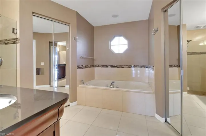 Full bath with tile patterned flooring, visible vents, a shower stall, a bath, and vanity