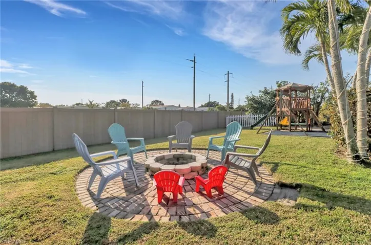 View of yard featuring a patio area, an outdoor fire pit, a playground, and a fenced backyard
