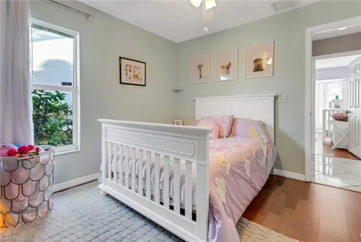 Bedroom with visible vents, multiple windows, baseboards, and wood finished floors