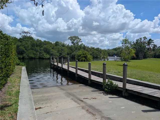 Dock area featuring a boat ramp, a water view, and a lawn