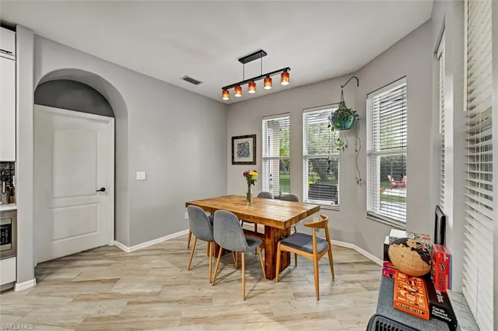 Dining area with arched walkways and light wood-style floors