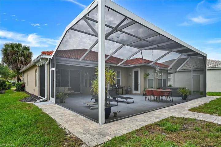 Back of house with a sunroom, a lanai, stucco siding, a patio area, and a tile roof