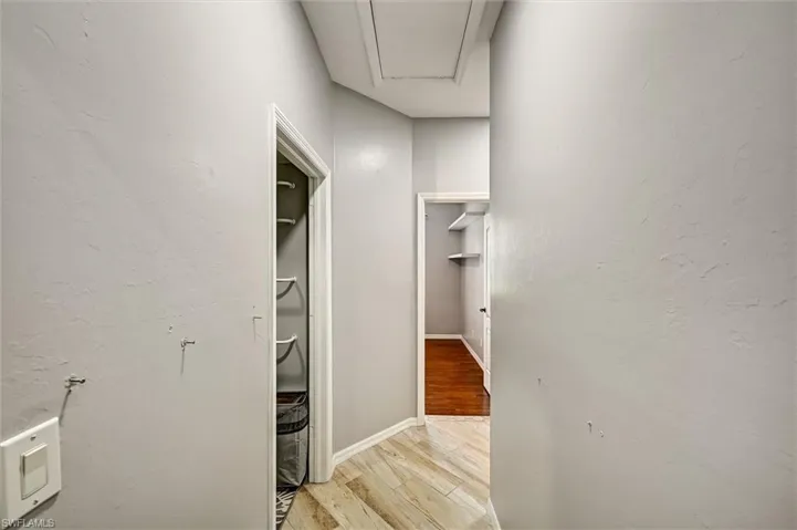Hall with light wood-style flooring and a textured wall