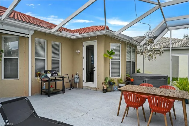 View of patio with a lanai, a hot tub, a sunroom, and outdoor dining area