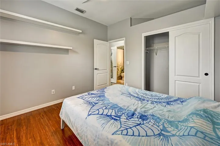 Bedroom with dark wood-type flooring, a closet, and a ceiling fan