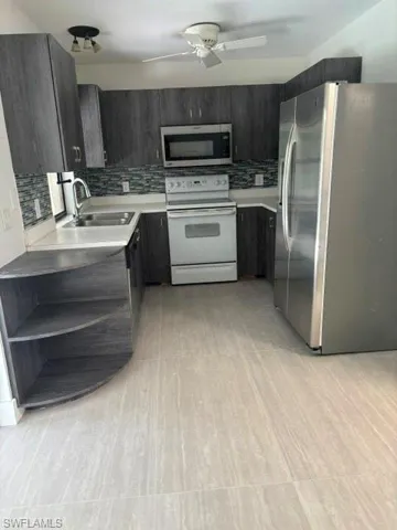 Kitchen featuring tasteful backsplash, fridge, white stove, and stainless steel microwave