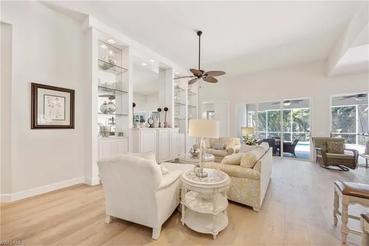 Living room with a ceiling fan, light wood finished floors, built in shelves, and baseboards