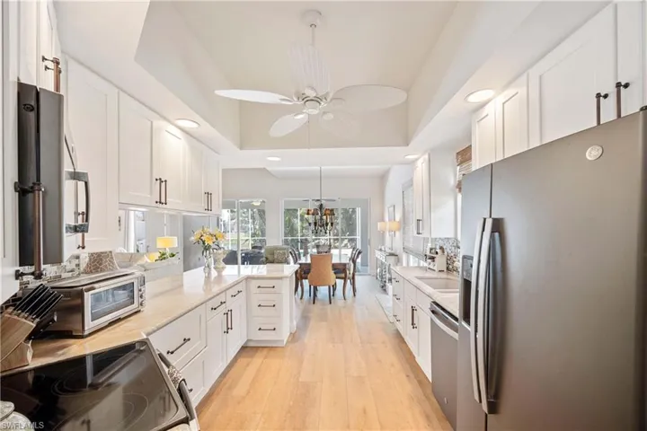 Kitchen with appliances with stainless steel finishes, white cabinetry, a raised ceiling, recessed lighting, and ceiling fan