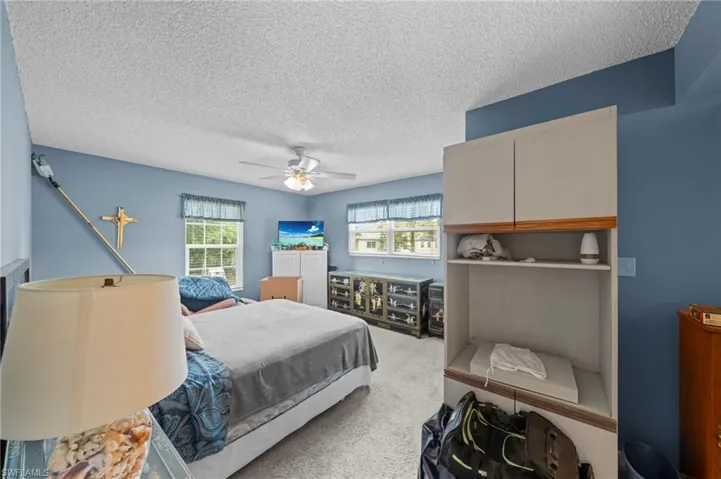 Bedroom with light carpet, a textured ceiling, and ceiling fan