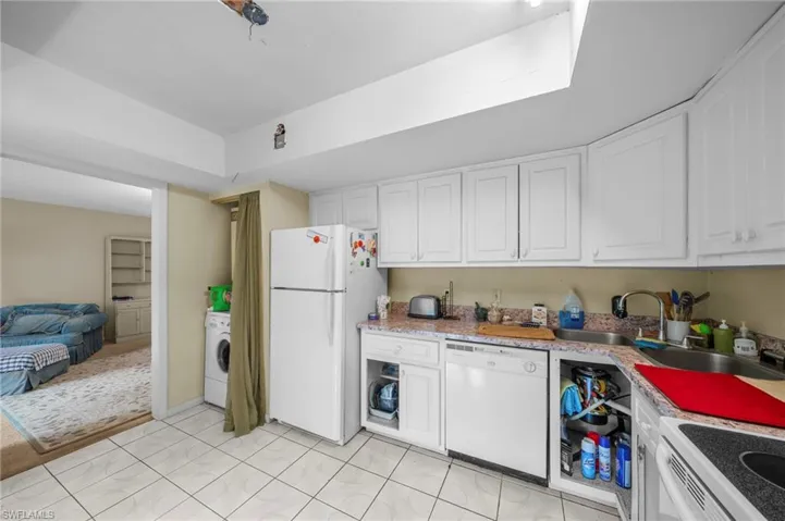 Kitchen featuring white cabinets, white appliances, and washer / dryer