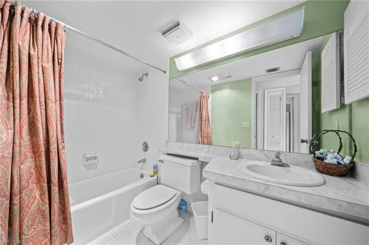 Bathroom featuring shower / bath combo with shower curtain, vanity, and tile patterned flooring