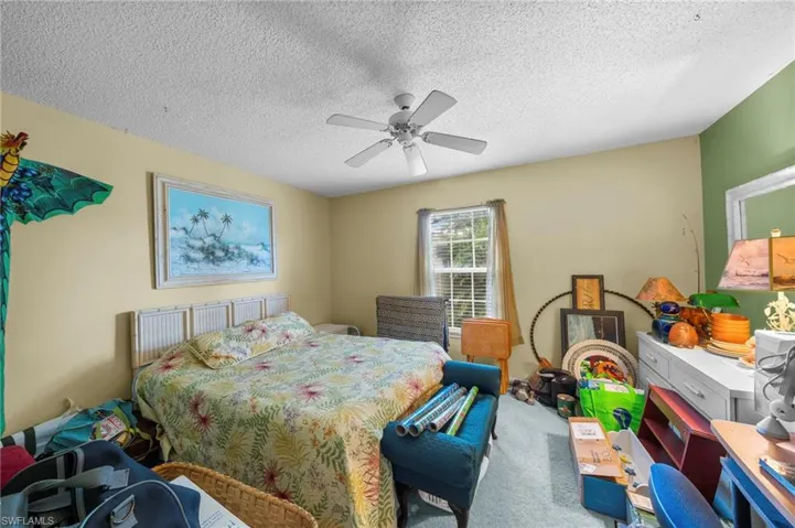 Carpeted bedroom featuring a textured ceiling and ceiling fan