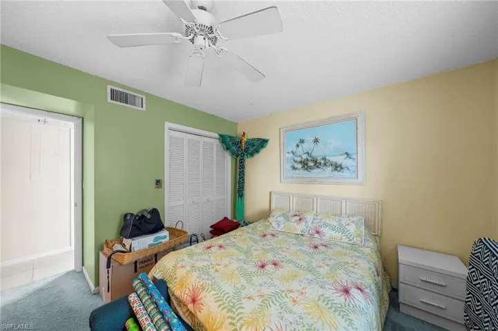 Carpeted bedroom featuring a textured ceiling, a closet, and a ceiling fan