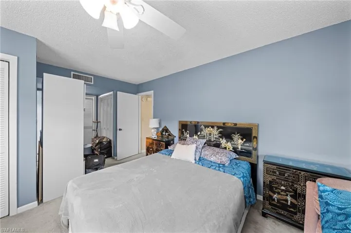 Bedroom with light carpet, a textured ceiling, a ceiling fan, and a closet
