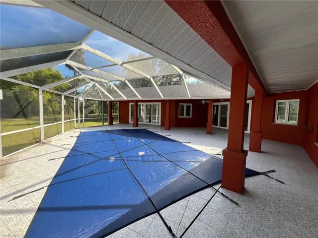 View of pool with a patio area, a covered pool, glass enclosure, and a sunroom