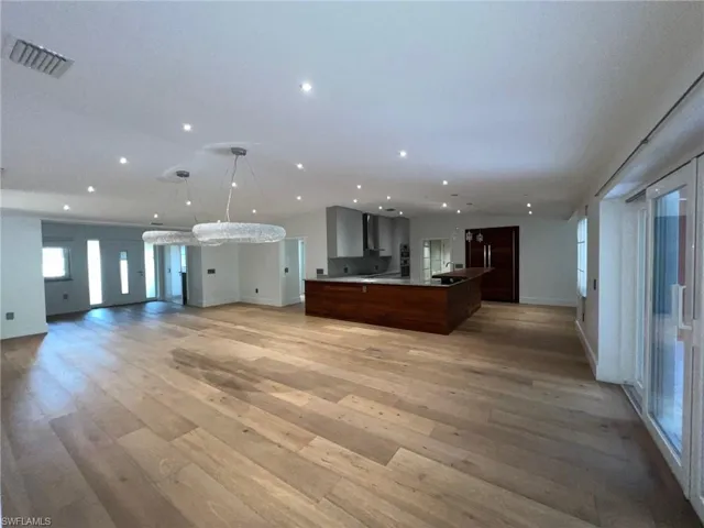 Unfurnished living room with light wood finished floors, recessed lighting, and vaulted ceiling