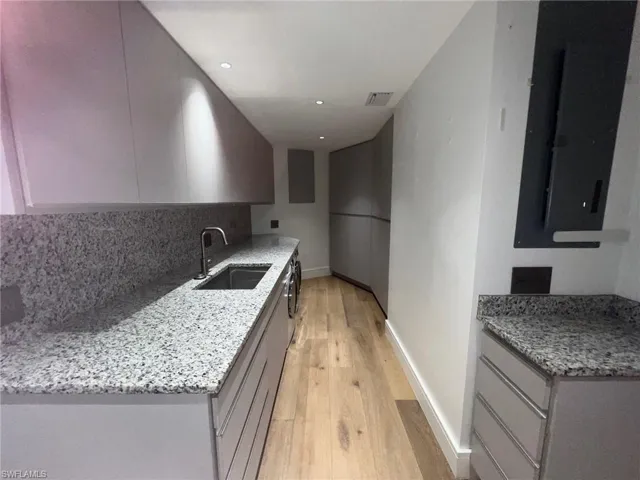 Kitchen featuring light stone counters, gray cabinets, tasteful backsplash, light wood-style flooring, and recessed lighting