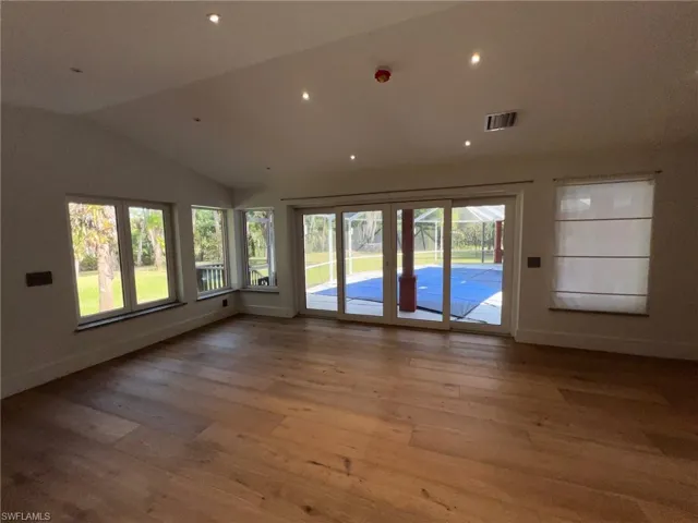 Spare room with vaulted ceiling, hardwood / wood-style flooring, recessed lighting, and healthy amount of natural light