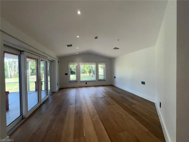 Unfurnished room with lofted ceiling, dark wood finished floors, and recessed lighting