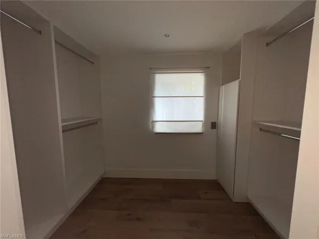 Walk in closet with dark wood finished floors