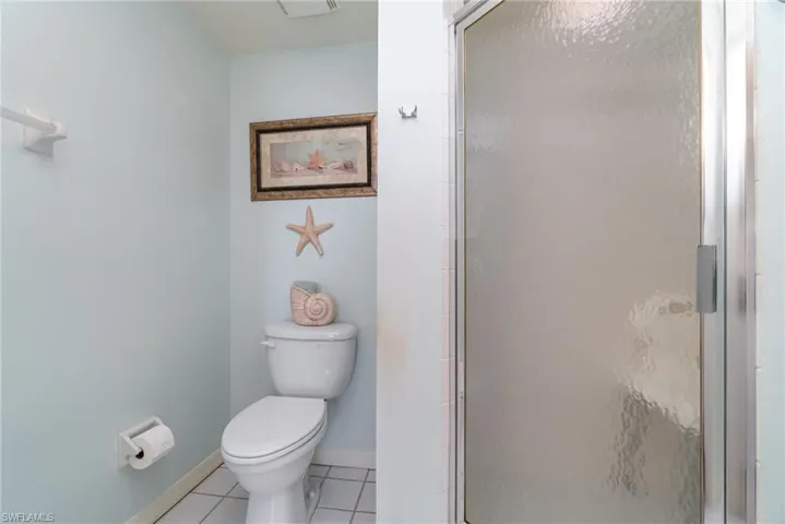 Bathroom with tile patterned flooring, walk in shower, and toilet