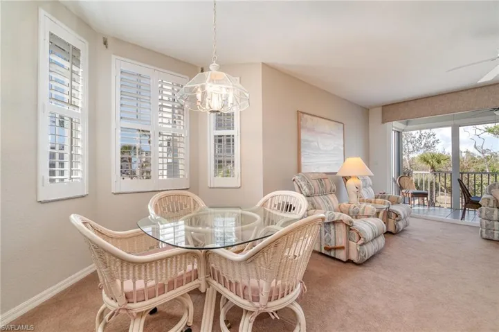 Carpeted dining area with ceiling fan with notable chandelier