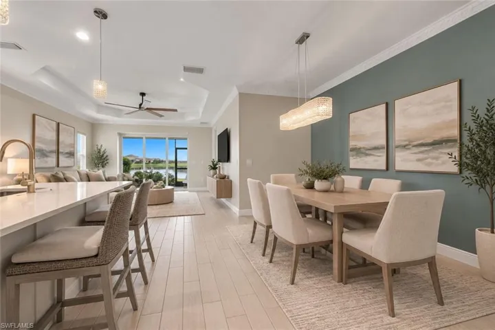 Open-concept living space with light wood-finish flooring, a tray ceiling, and crown molding