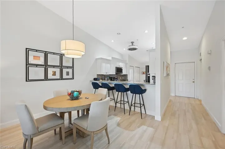 Dining room with light hardwood / wood-style floors and high vaulted ceiling