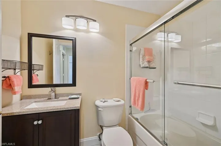 Full guest bathroom featuring vanity, toilet, and combined bath / shower with glass door