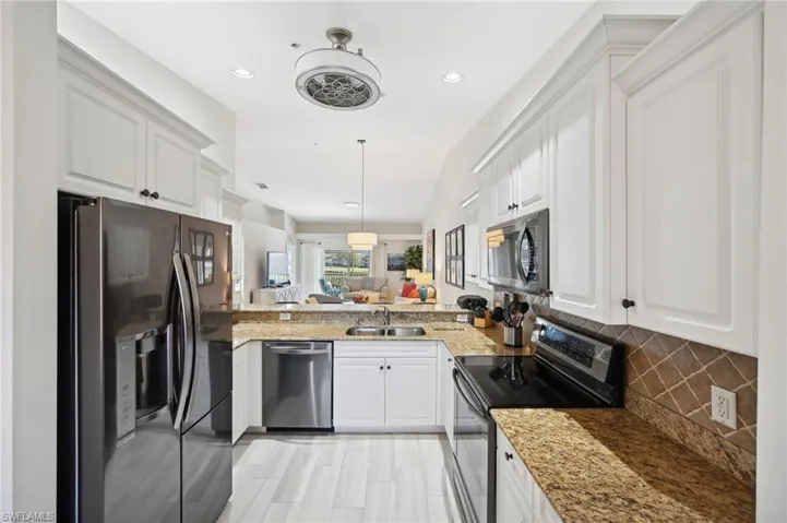 Kitchen featuring white cabinetry, sink, stainless steel appliances, kitchen peninsula, and pendant lighting