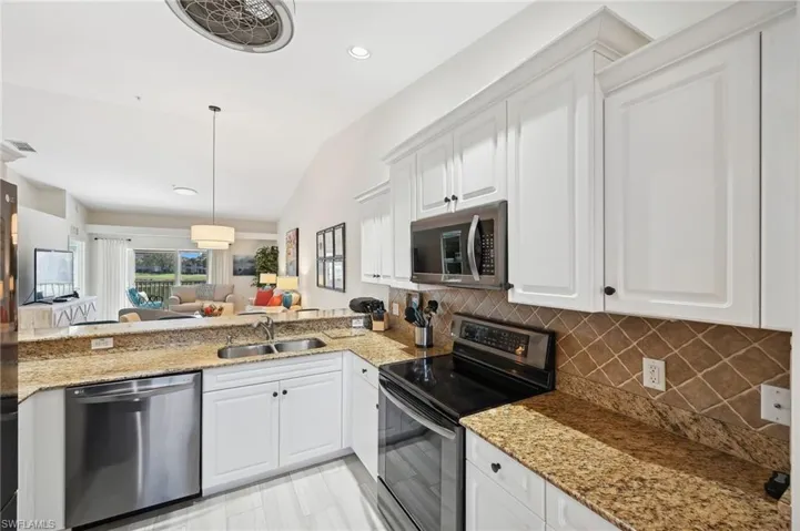 Kitchen with white cabinetry, sink, appliances with stainless steel finishes, and vaulted ceiling