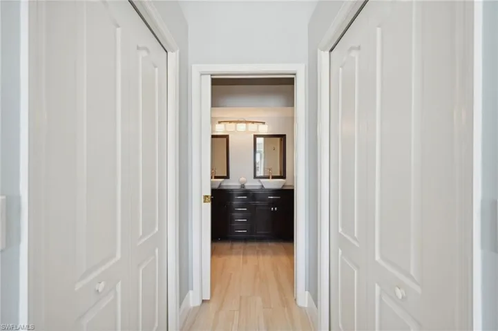Hallway Closets leading to Primary Bathroom featuring dual sinks and shower