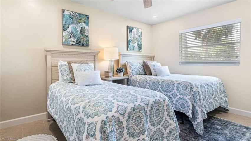Tiled bedroom with ceiling fan and baseboards
