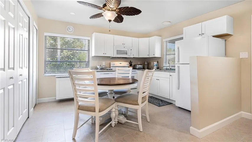 Kitchen with white appliances, white cabinetry, ceiling fan, and baseboards