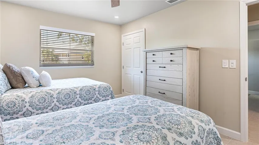 Bedroom featuring ceiling fan, light tile patterned flooring, visible vents, and baseboards