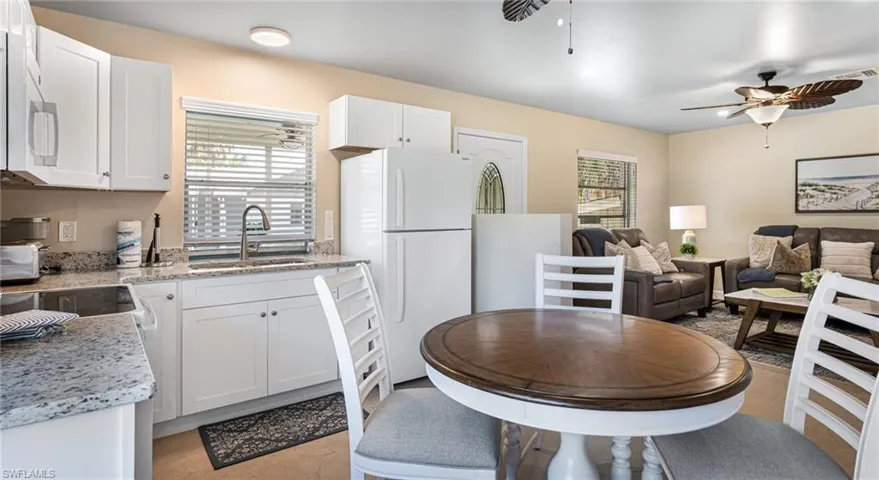 Kitchen featuring white appliances, ceiling fan, white cabinetry, and a sink