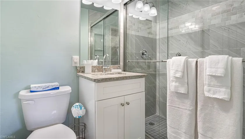 Bathroom featuring a stall shower, vanity, and toilet