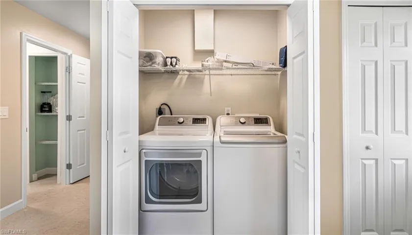 Laundry area with laundry area, light tile patterned floors, baseboards, and washing machine and clothes dryer