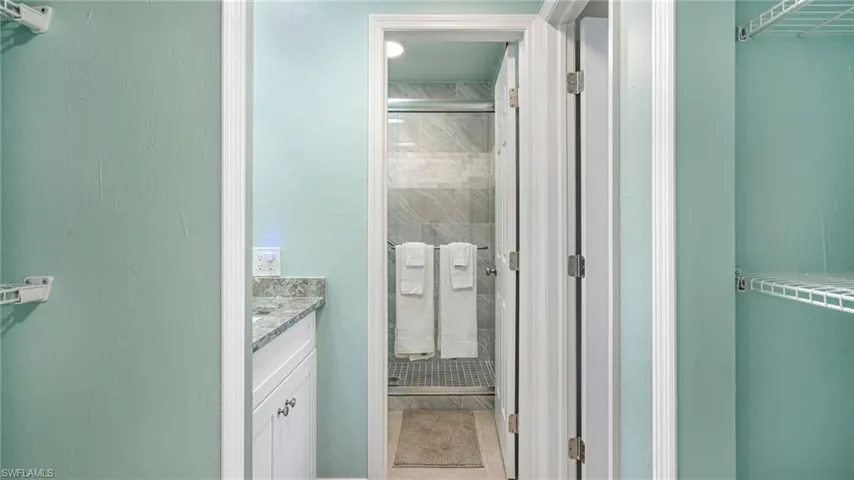 Bathroom with a shower stall, a walk in closet, tile patterned flooring, and vanity