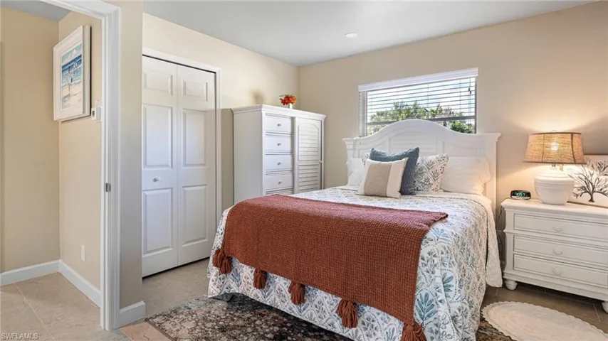 Bedroom featuring a closet, light tile patterned flooring, and baseboards